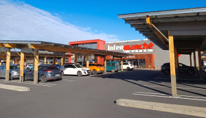 Ombrières solaires à structure en bois couvrant les places d'un parking de supermarché